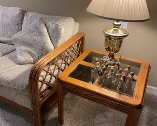 Rattan couch, smoked glass and maple side table, brass lamp, and Willow tree figurines