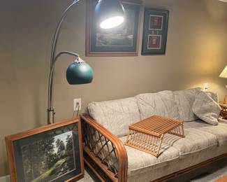 Another view of the Rattan couch, Mid-Modern floor lamp, bed tray, and framed prints
