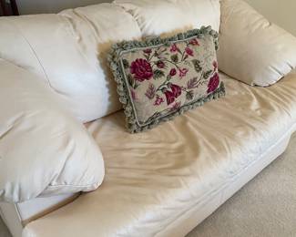 Another view of the leather loveseat with a needlepoint accent pillow