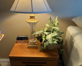 2-drawer nightstand, brass and glass lamp, Sharper Image clock and faux plant