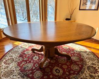 Large 72” diameter oak wood dining table.  The top to this table is one solid piece and comes with full table pads, four side chairs and two captains chairs