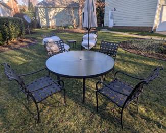 B8 - $300.  Brown Jordan Patio Set.  2 Chairs w/ottomans and side table. Table w/umbrella and four chairs. Some visible peeling.  Pillows wrapped to protect from weather. 