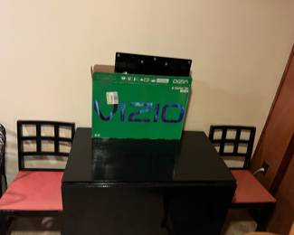 Large black drop leaf table with chairs.  VIZIO TV set
