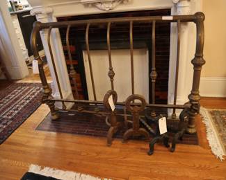 Footboard of an old brass bed with two sets of iron andirons in the downstairs stair room.