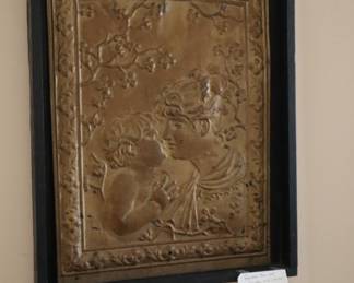 The embossed metal fireplace screen, hanging on the wall in the lower staircase room.