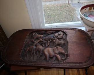 A carved flat top for a table from Africa with a cross wooden base. In the upstairs.