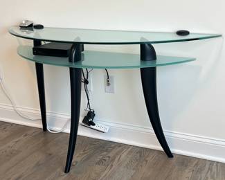 Glass Demilune Table | Modern glass side table with medial shelf, over three splayed legs; n.b. electronics not included. - h. 28.75 x l. 55 x d. 17.75 in
