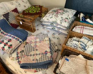 Numerous quilts & pillows. Nice kitchen towel collection. Wicker lap tray
