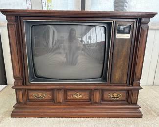 Perfectly preserved Zenith Space Command System 3 Project TV, likely from the 1970s. Key features include:
Brand: Zenith, an American consumer electronics company now owned by LG Electronics. 
Type: Console television, a style popular in the mid-20th century.
Features:
Wood cabinet with decorative details.
Analog CRT screen.
Includes "Space Command" remote control functionality.
Drawers at the bottom for storage. 