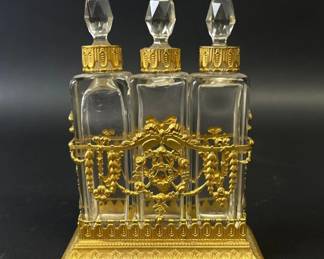 Three French perfume bottles in gilded metal caddy