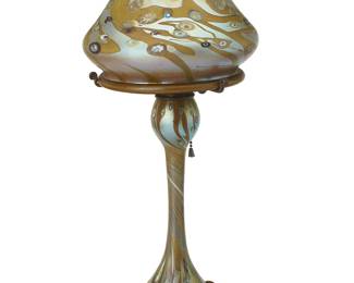 1095
1983
A Carl Radke art glass boudoir lamp
Etched to underside: Carl Radke / Phoenix Studio / 83; shade etched at rim: Carl Radke / 83
The single-light lamp with iridescent glass mushroom shade decorated with murrini cane accents, mounted to a conforming base, electrified
Overall: 18" H x 8.25" Dia.
Estimate: $300 - $500