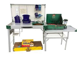 ANMA628 Coleman Kitchen And Cookware Assortment This lot includes a Handy foldable table and chairs set, Coleman 425E dual flame grill, Coleman kitchen model 840-700with bag and instruction manual,