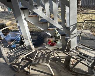 Two outdoor patio rocking chairs, with a foot rest and side table. 