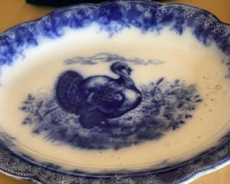 Wedgwood Clytie Flow Blue Turkey Platter.
It is an antique English platter.
The pattern is "Clytie" with a turkey motif.
It is made of flow blue semi-porcelain.
The platter has a scalloped rim and floral border.
The maker's mark is on the underside.
It was produced by Wedgwood in England.
The platter dates back to the 19th century.
It measures approximately 18 x 13.5 inches.