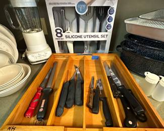 Here is a container of very sharp knives and knife sharpeners! The eight piece silicon utensil sit in the back is brand new and has never been opened!