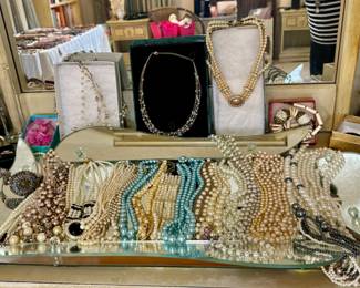 The pearl necklace shown on the box on the right and the pearl necklace on the tray with the black center are sold.