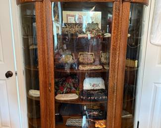 Tiger oak bow front China cabinet filled with vintage evening bags