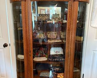 Tiger oak bow front cabinet filled with vintage clutches