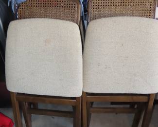Four cane back wooden folding chairs with fabric seats.