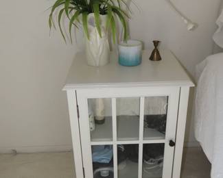 White night stand with glass door.
