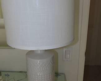 One of two matching white ceramic table lamps.