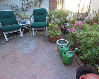 Patio chairs, end table, pots, plants and watering cans.