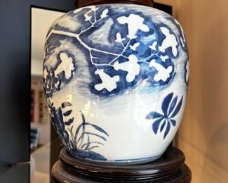 Chinese Blue and White Porcelain Vase, likely from the Qing Dynasty, Kangxi-style. 
 Traditional blue designs on a white background, depicting a tree with birds. 
The vase includes a black lid and a matching wooden base