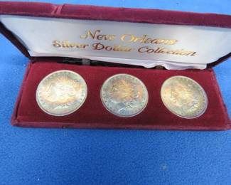 Lot 414. Three toned Morgan silver dollars minted in New Orleans in a presentation box: 1884,1885, and 1904.