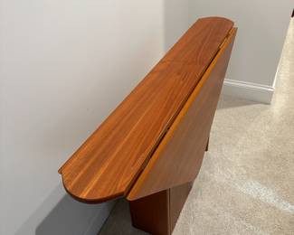 F94 - $950. Danish Teak Triangular Drop Leaf Table. Sides drop down making it narrow enough for a hallway or sofa table but opens large enough for 4 people. Measures 10" wide when folded down x 52" long. Each leaf comes up 22". So a 52" x 54" almost square!