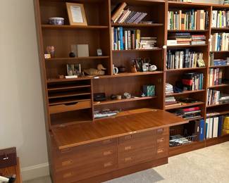 F121 - $1200. Mid Century Teak Wall Unit moves in 3 pieces. Minor water (?) damage to one drawer. All drawers slide easily. Assembled Both Sections measure 54.5" wide x 12" deep x 76.5" tall. (desk out measures 29".) Base on left is 3rd piece. 54.5" wide x 17" deep. 