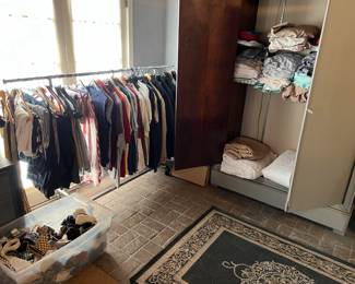 There is a rack of clothing here, and you can see the bedding in the large closet.