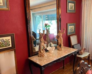 Here you can see a pair of matching chairs on either side of a table with a male and female statuette inspecting grapes.  There is also the large wall mirror, of course, and the four framed art pieces on the wall.