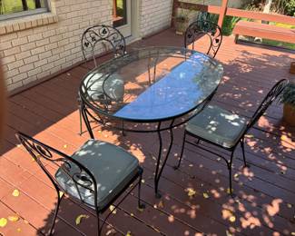 Wrought Iron Oval glass top Table with 4 chairs. T: 54”L 36”d 29.5”t. C: 16”x16”x 36”.  
