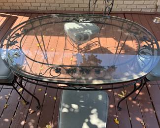 Wrought Iron Oval glass top Table with 4 chairs. T: 54”L 36”d 29.5”t. C: 16”x16”x 36”.  