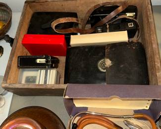 The box is full of antique cameras in their original leather casings. Two “A.M.” transistor radios. 