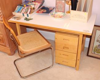 Desk with drawers and cane chair.