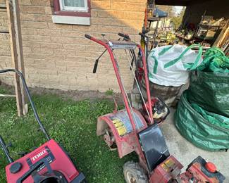 Two different rototillers and a snowblower in the top right of the picture are giant lawn bags!