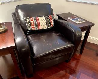 Dark brown distressed leather chair with decorative pillow, side tables