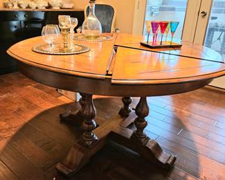 Round dining table with petal and pie shapes extension inserts.