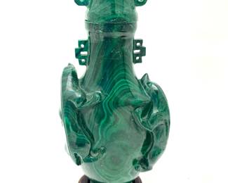 LOT 47 Register: www.woodardlipe.com CHINESE CARVED BANDED MALACHITE VASE WITH LID ON ROSEWOOD BASE Height 4.5 in, width 2 in., depth 1 in; without stand. mineral weight 233 grams, Carved lidded banded malachite bottle with stylized serpents on side, metal inlay on base. Malachite, a semi-precious stone with deep green hues and unique patterns, has many meanings and uses: Ancient civilizations used malachite to ward off evil spirits and witchcraft, and to protect against the evil eye. Malachite is associated with good luck, wealth, and health. It's also known as the Stone of Transformation and is said to attract luck and dispel negativity.