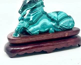 LOT 45 Register: www.woodardlipe.com MALACHITE CARVED HORSE ON WOODEN BASE Length 4 in., height 2.5 in., width 1 in., Mineral weight, 178 grams. Malachite is the essence of joy and is known as the stone of transformation because it helps reveal and heal emotional pain by absorbing the pain into itself. It is especially helpful in bringing ease during times of change and gives the insight needed for personal growth.