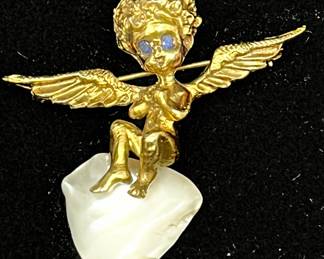 LOT 120 Register: www.woodardlipe.com 14K WILLIAM RUSER STYLE CHERUB BROOCH ON PEARL WITH SAPPHIRE EYES Height 1.5 in, width 1.5 in. Total weight 12 grams. Vintage mid-century brooch in the style of William Ruser features a stylized cherub with sapphire eyes sitting on a pearl cloud. This unique piece is indicative of the famed jeweler's style and features a charmingly sculpted, curly-haired cherub.