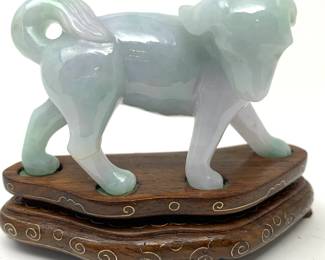 LOT 31 Register: www.woodardlipe.com JADEITE DOG ON WOOD STAND WITH BRASS INLAY Length 3 in, height 2 in, width 1 in. Mineral weight, 74 grams. Chinese jadeite carved dog on carved wooden base with brass inlay, Condition report: small crack on rear leg.