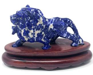 LOT 44 Register: www.woodardlipe.com CARVED LAPIS LION ON WOODEN BASE Length 4.5 in., height 2.5 in., width 1.5 in., Mineral weight, 198 grams.