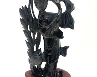 LOT 70 Register: www.woodardlipe.com BLACK OBSIDIAN KWAN YIN STATUE WITH FLOWER AND BIRD AT FEET Length 3.5 in, width 1.5 in. height 7 in, Weight 364 grams with base. Mid-century carved statue of Kuan Yin on rosewood base with elaborate background of flora, single flower with a bird at her feet.