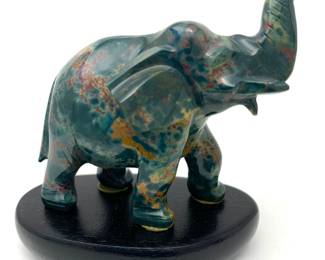 LOT 28 Register: www.woodardlipe.com CHINESE CARVED BLOODSTONE FIGURE OF ELEPHANT Length 2.75 in., heigh 2.25 in. width 1.25 in. Carved elephant with raised trunk on wooden base. A bloodstone elephant is a handcrafted sculpture that combines the healing properties of bloodstone with the symbolism of an elephant. Elephants are associated with wisdom, strength, protection, and luck. Bloodstone is said to have grounding energies and can help increase courage, vitality, and emotional balance.