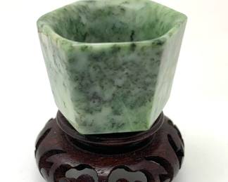 LOT 74 Register: www.woodardlipe.com JADE CUP WITH HEXAGONAL SIDES ON ROSEWOOD BASE Diameter 1.5 in., height 1 in., Small carved jade cup on Rosewood base.