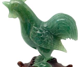LOT 33 Register: www.woodardlipe.com HAND-CARVED AVENTURINE ROOSTER ON STAND Length 3 in, depth 1 in, height 3 in. without stand. Weight 87 grams. Hand-carved green aventurine rooster. Aventurine is a variety of quartz and gets its name from the Italian phrase a ventura (by chance) due to its similarity in appearance to goldstone, already known as aventurine. Aventurine is typically green and is the alternate birthstone for the month of August.