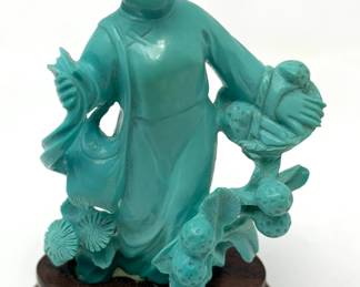 LOT 50 Register: www.woodardlipe.com HAND CARVED TURQUOISE WOMAN WITH FLOWERS AND BASKET Length 1.75 in, width 1i n, height .2.75 in. Weight 39 grams. Standing hand-carved turquoise woman with elaborate floral motif and basket in her arms. Figure is attached to rosewood base with delicate brass inlay detail. The turquoise stone has many meanings, including good fortune, protection, emotional balance and stress relief.