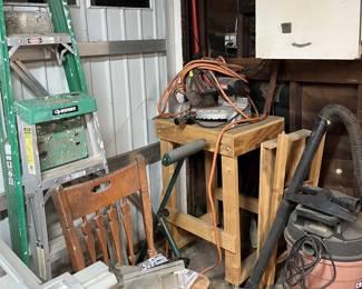 On the wooden table is a compound mitre saw.  You can also see the two ladders on the left and the large shop vacuum on the right.
